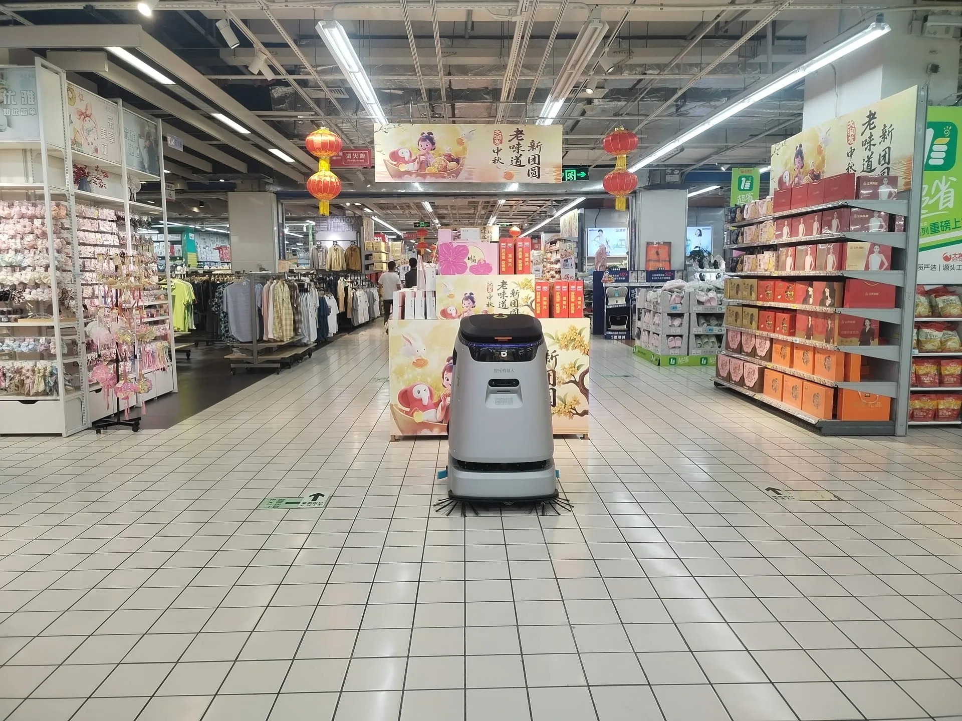 A cleaning robot working down the wide aisle of a supermarket