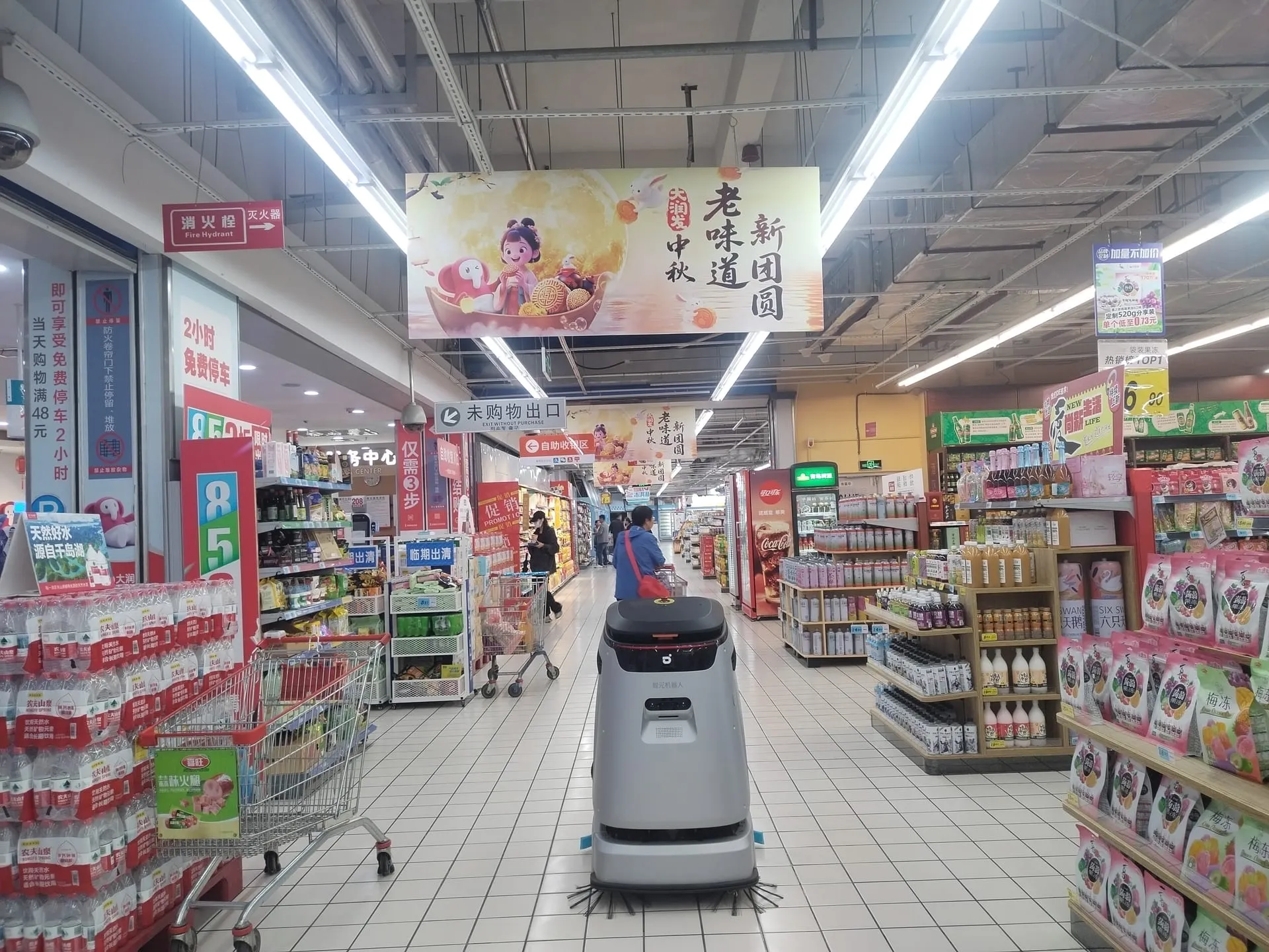 一台清洁机器人在人流密集的超市通道中作业